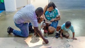 A black family with two young children drawing together at Torpedo Factory Art Center